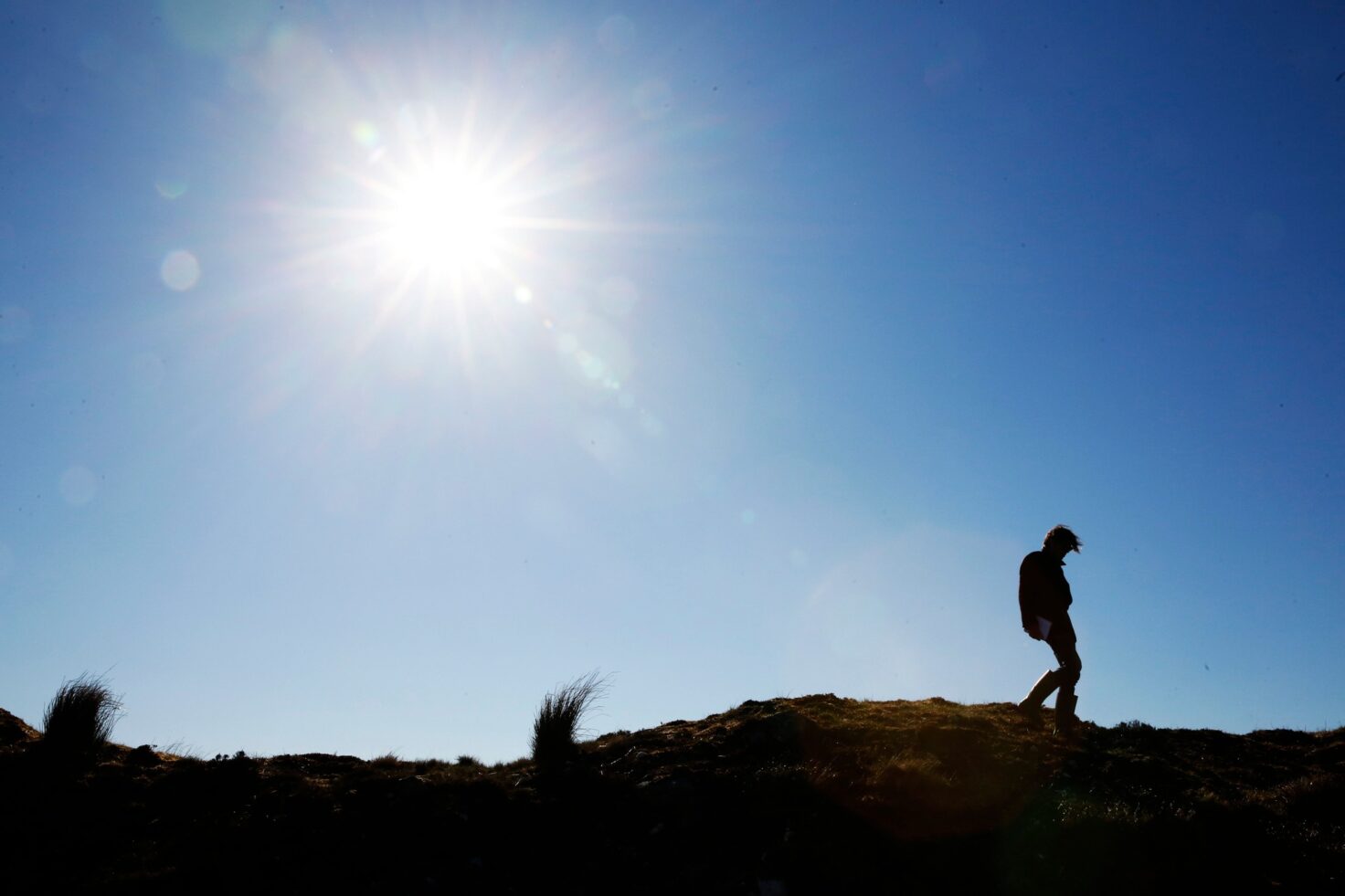 A person walks across the skyline in the Flow Country with the sun shining.